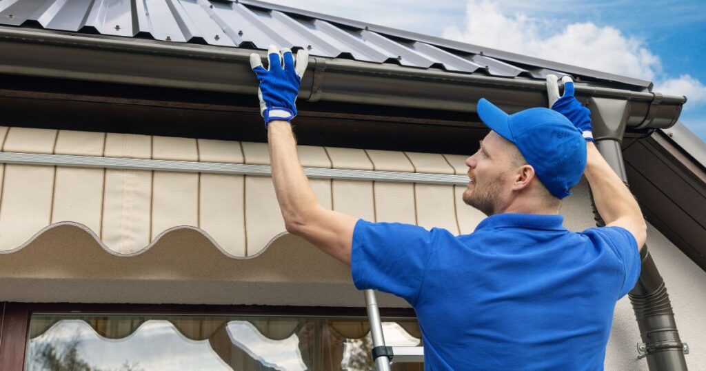 Worker installing seamless gutters on home